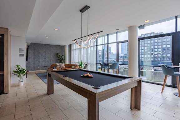 A pool table is in the middle of a room with a view of the city.