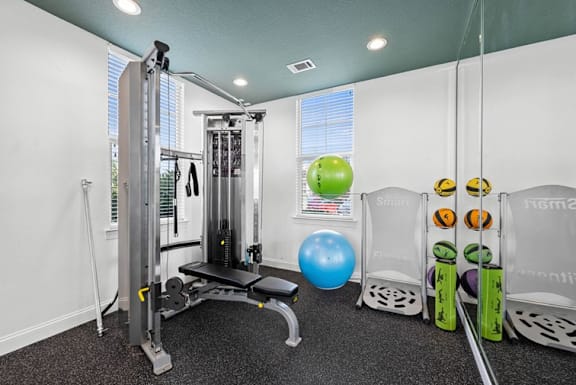 A gym with a weight machine, a bench, and exercise balls.