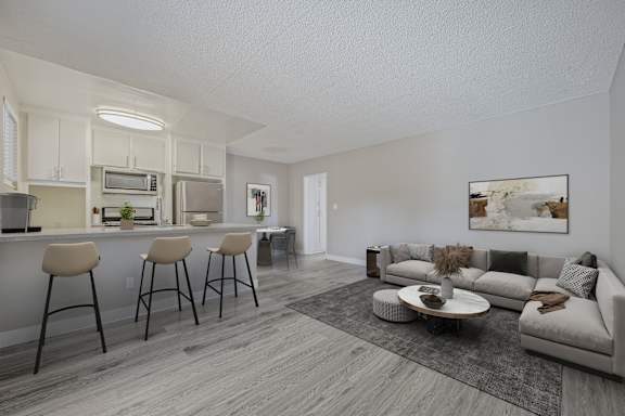 A modern kitchen with white cabinets and a bar area with stools.
