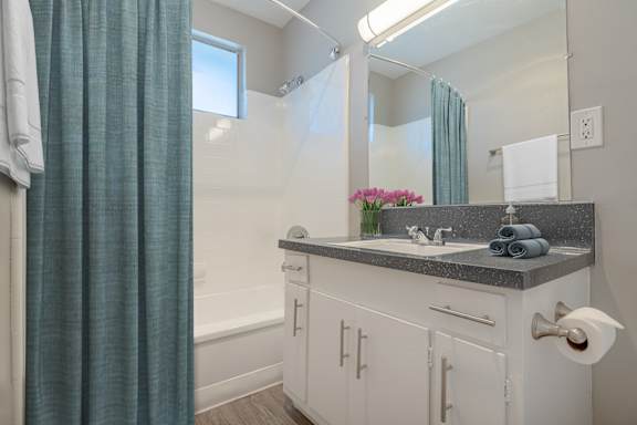 A bathroom with a white sink and a window with a blue curtain.