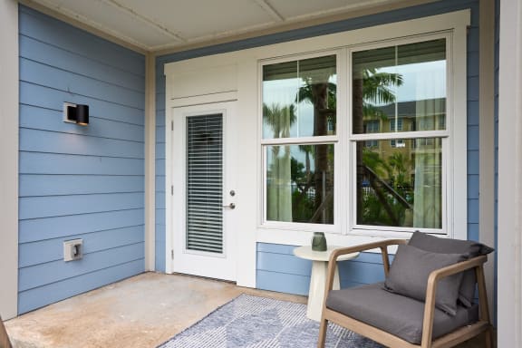 a chair and a table on a porch next to a door