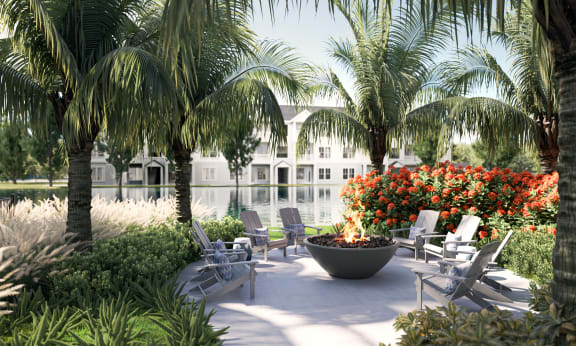 a patio with chairs and a fire pit in front of a body of water and palm trees