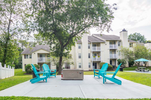 a fire pit and lounge chairs sit on a concrete patio in front of an apartment building at Hamilton at Kings Place, Columbia, 21046