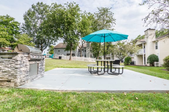 a patio with a table and umbrella and a grill at Hamilton at Kings Place, Columbia, MD
