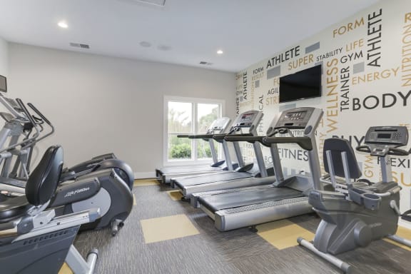 a gym with four treadmills and a television at Madison at Eden Brook, Columbia, MD
