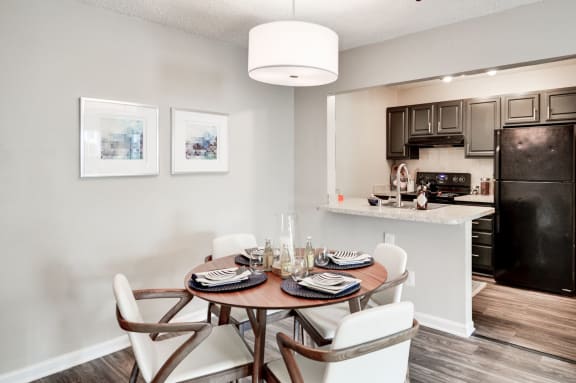 a dining area with a table and chairs and a kitchen in the background at Hamilton at Kings Place, Columbia, MD