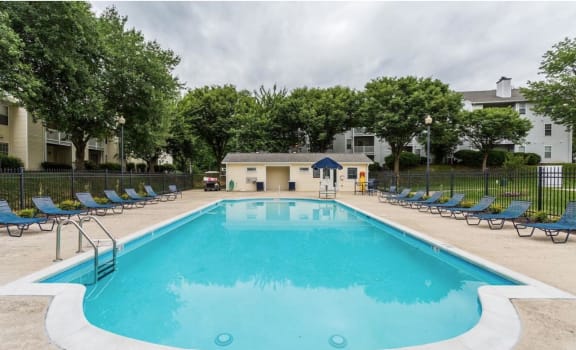 a swimming pool with chaise lounge chairs and an apartment building in the background at Madison at Eden Brook, Columbia