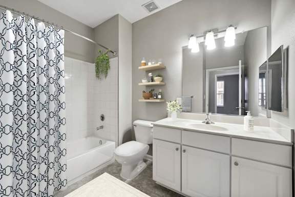 A bathroom with a white toilet, sink, and a shower with a black and white curtain.