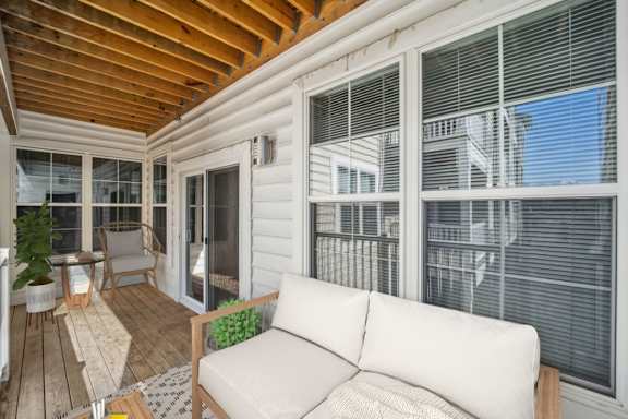 A white couch is on a wooden deck with a table and chairs.