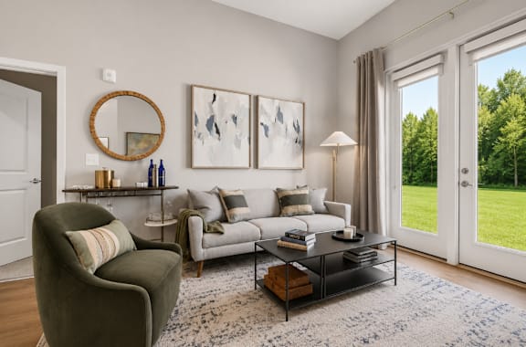 A living room with a grey couch, a brown armchair, a coffee table, and a large window with a view of a green lawn.
