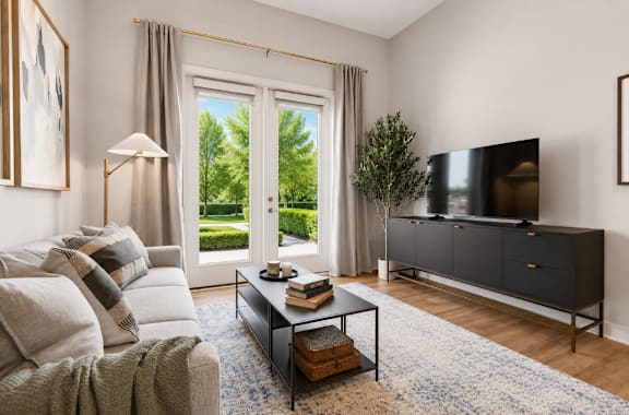 A living room with a grey sofa, a black cabinet, and a large window with curtains.