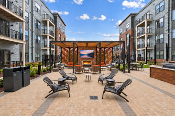 A modern outdoor seating area with black chairs and tables is surrounded by apartment buildings.