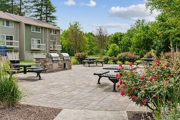 Outdoor grilling area with paver patio and seating at The Brook At Columbia Apartments, Maryland