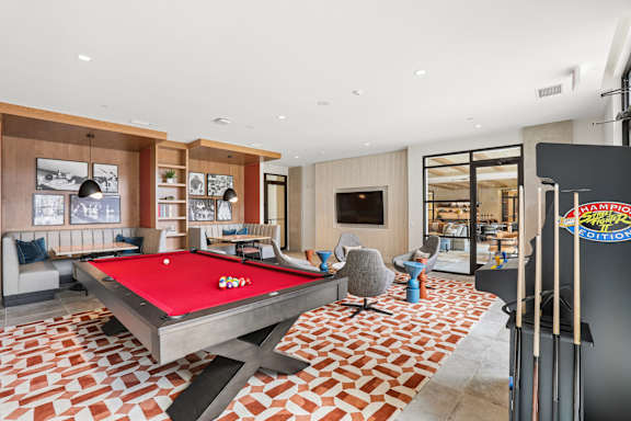 A pool table is in the middle of a room with a red cloth.