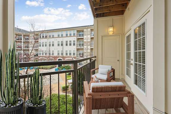 A balcony with a table and chairs overlooks a courtyard.