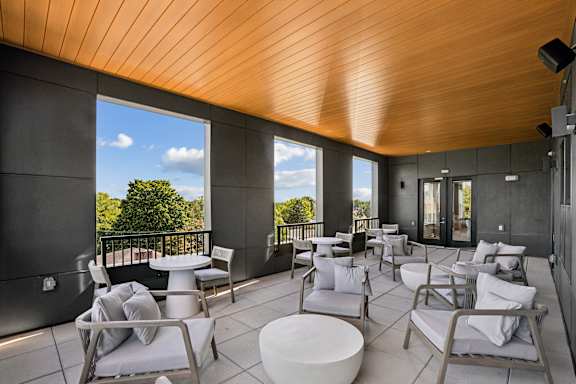 A patio with white furniture and a wooden ceiling.