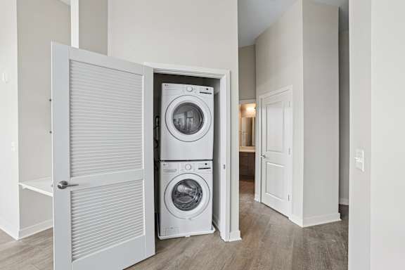 A white door is open to a room with a washer and dryer in it.