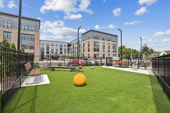 A playground with a green lawn and a yellow ball.