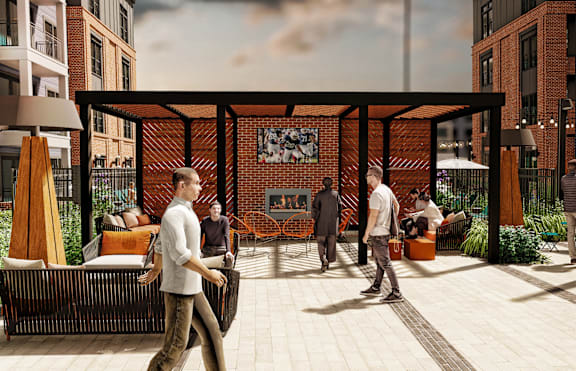 A group of people are walking around a courtyard with a brick wall and a fireplace.
