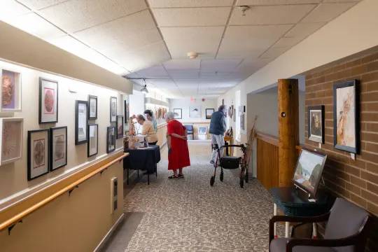 A hallway with people and framed pictures on the wall.