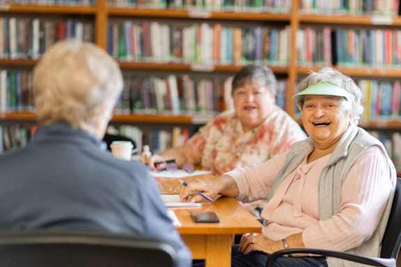 Three people sitting at a table in a library.