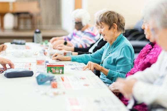 A group of elderly people are sitting around a table playing a board game.