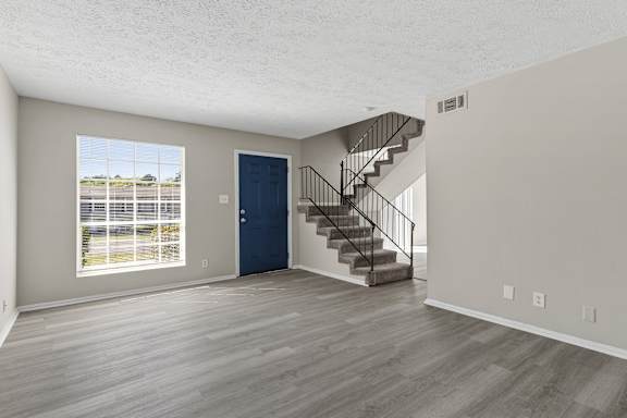 A room with a blue door and a staircase.