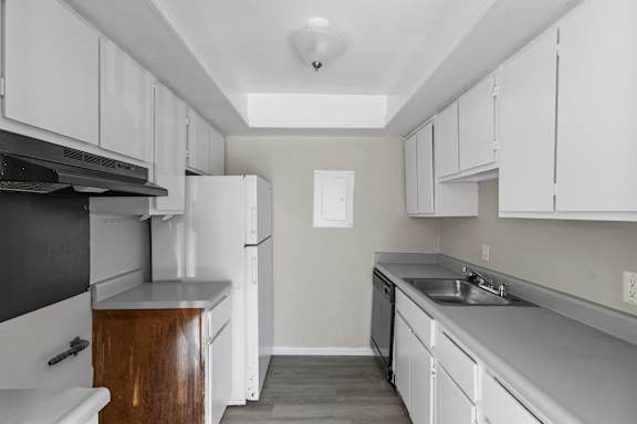 A kitchen with white cabinets and a black counter top.