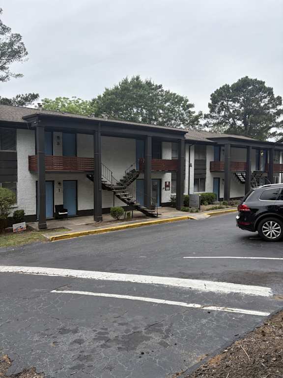 A black car is parked in a parking lot in front of a building.