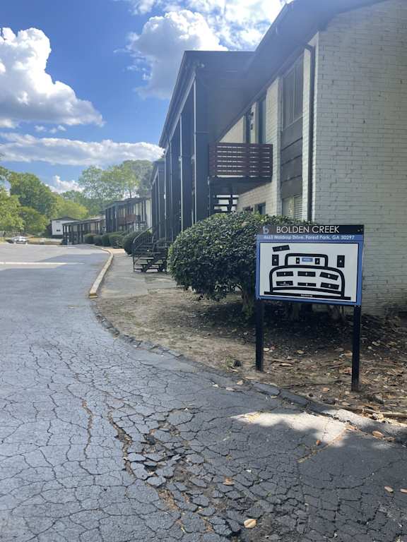 A sign for Bolden Creek stands in front of a building.