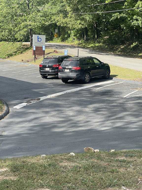 Two cars are parked in a parking lot with a sign that has a letter "b" on it.