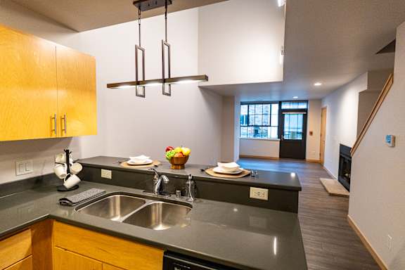 A modern kitchen with a black counter top and wooden cabinets.