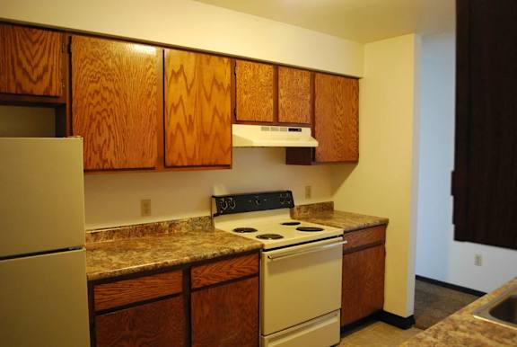 A kitchen with a white stove and wooden cabinets.