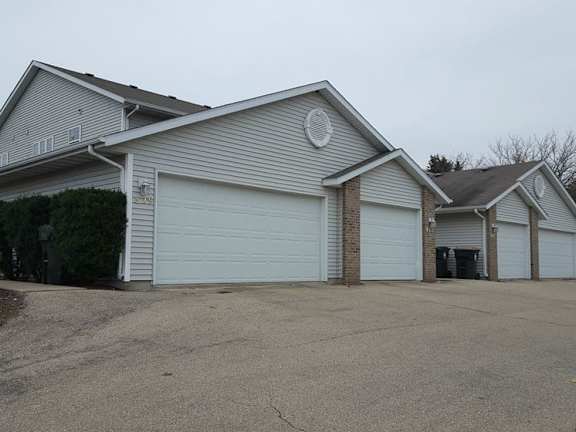 A two-story house with a garage door open.
