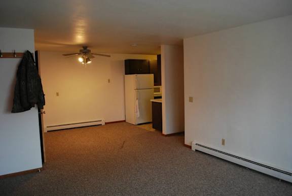 A room with a ceiling fan and a refrigerator.