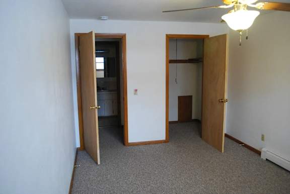 A room with a ceiling fan and two open doors.