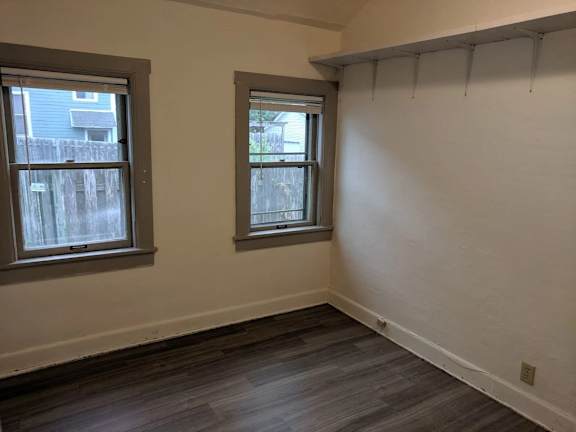 A room with two windows and wooden floors.