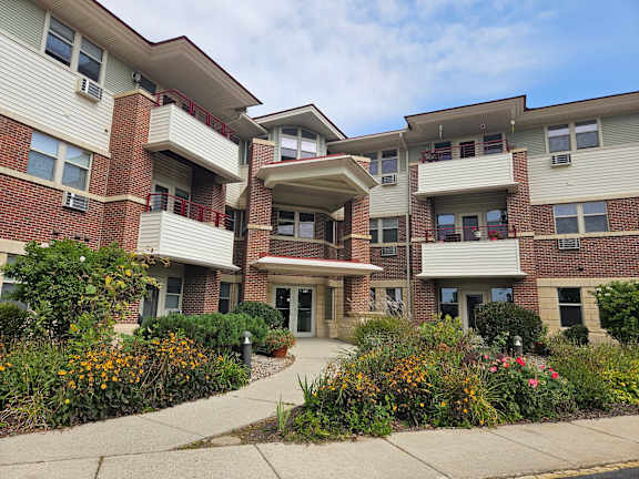 A multi-story apartment building with a landscaped front yard.