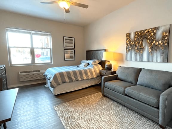 A bedroom with a bed, a couch, and a ceiling fan.