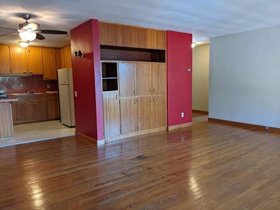 A kitchen with wooden floors and a red wall.