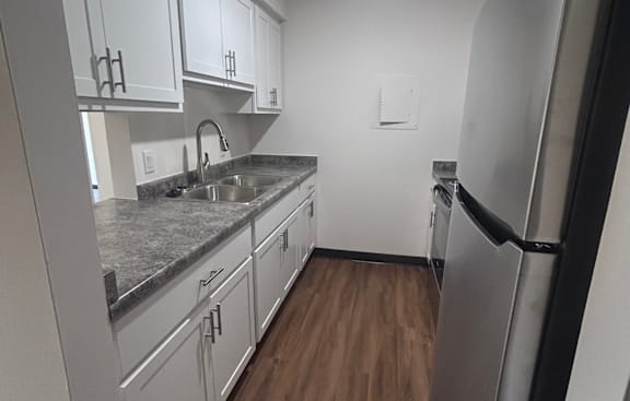 A kitchen with white cabinets and a granite countertop.