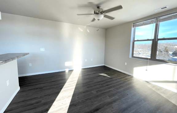 A room with a ceiling fan and a large window overlooking a snowy landscape.