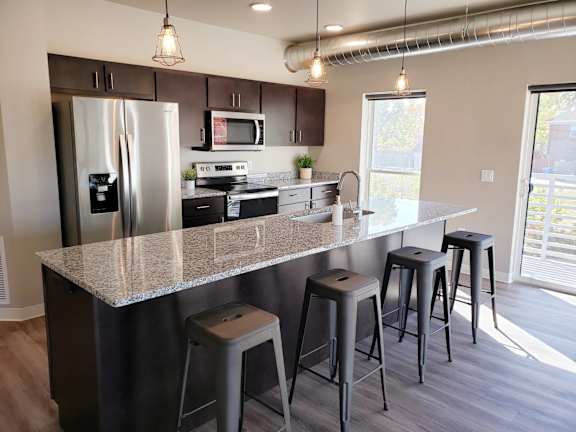 A kitchen with a granite countertop and a refrigerator with a water dispenser.