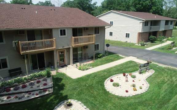 A small garden with a heart-shaped flower bed in front of a building.