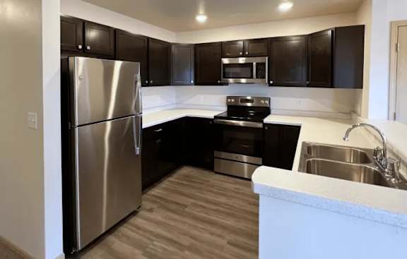 A modern kitchen with a stainless steel refrigerator and black cabinets.