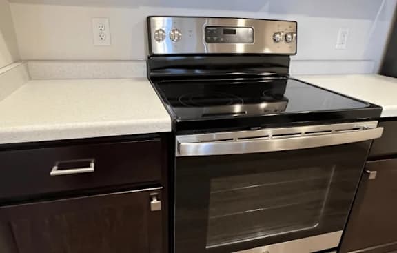 A modern stainless steel oven with a digital display is installed in a kitchen.
