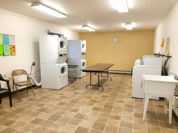 A laundry room with a washer and dryer, a table, and chairs.