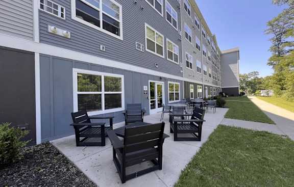 A sunny day at a residential building with a patio and chairs.
