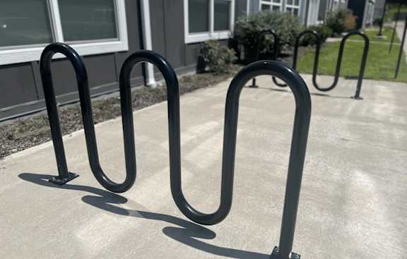 A set of black metal bike racks are on a concrete surface.