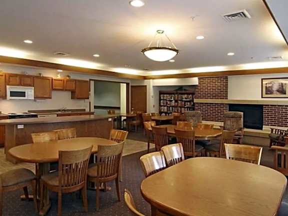 A room with tables and chairs and a brick wall.